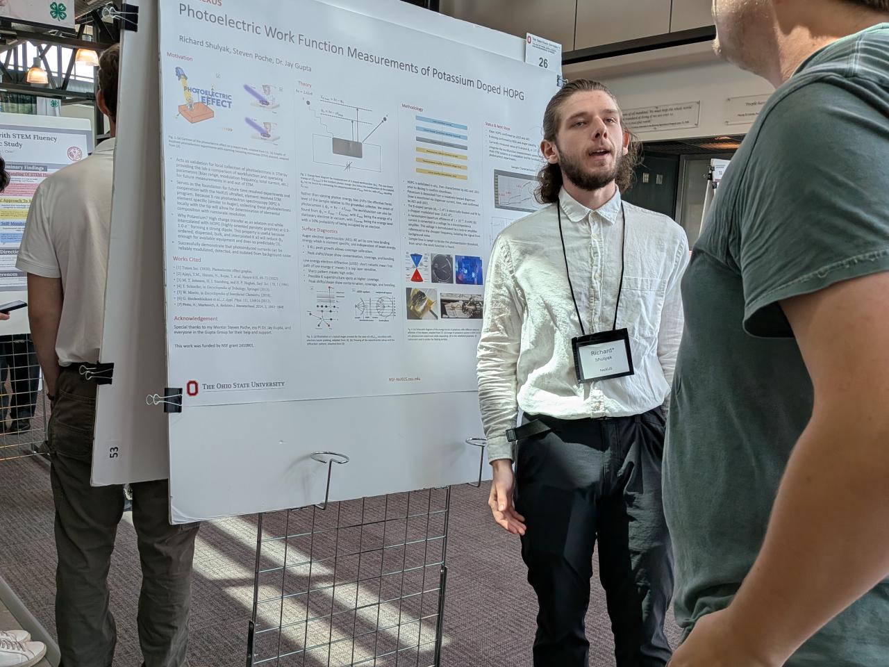 Richard Shulyak presents his research poster to a listener