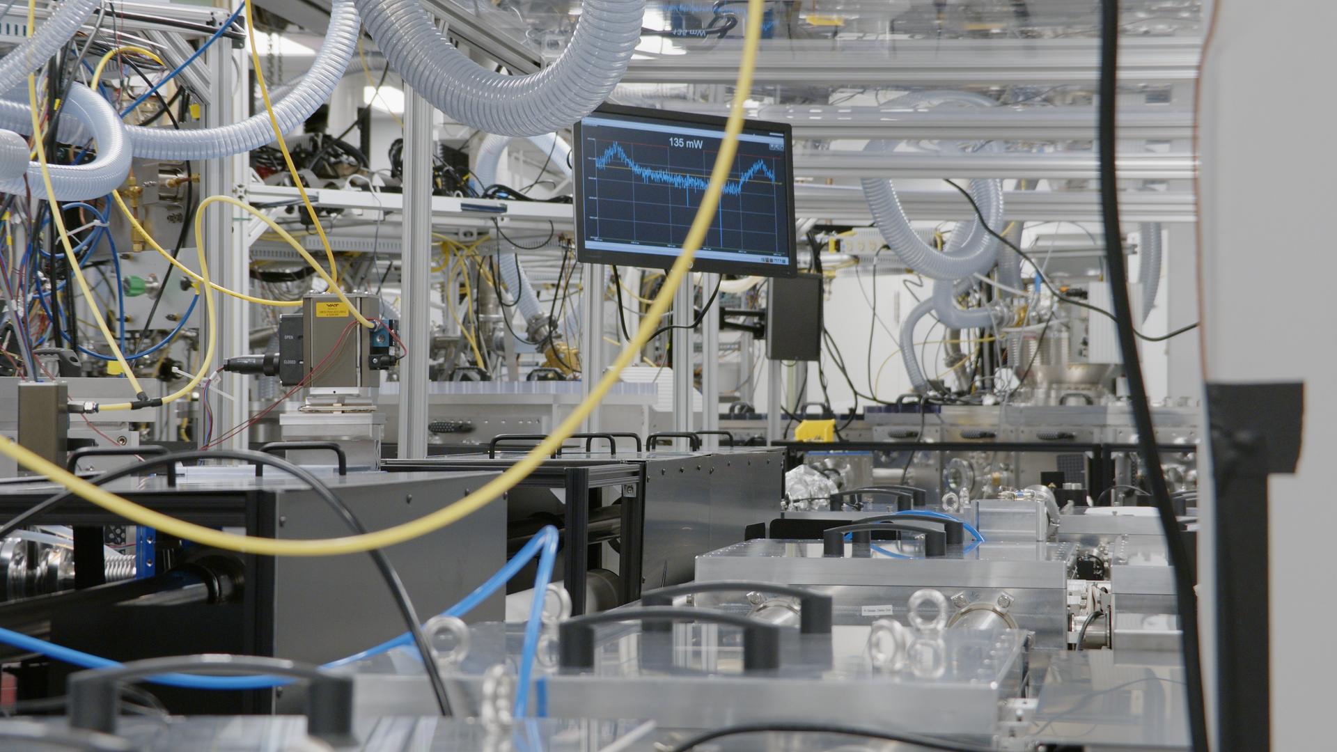 View of the laser table with multiple vacuum chambers and a computer monitor with graphical readout