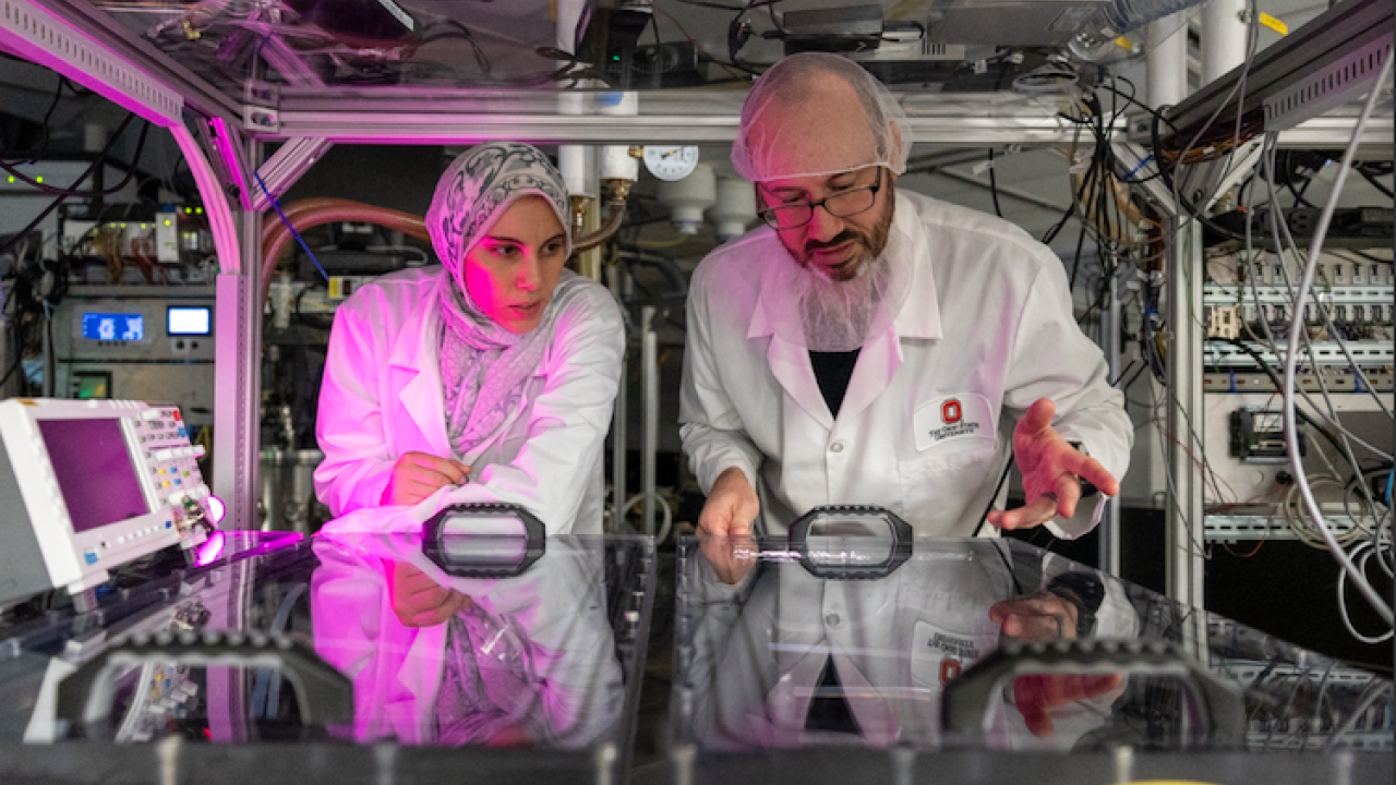 Dina Eissa and Tim Scarborough looking into vacuum chambers in the NeXUS lab