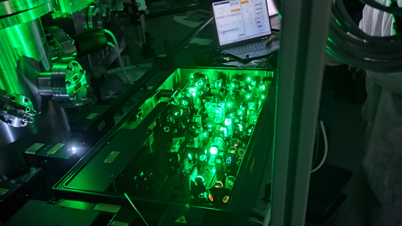 Green light traveling through multiple sets of optical lenses and mirrors inside a laser chamber
