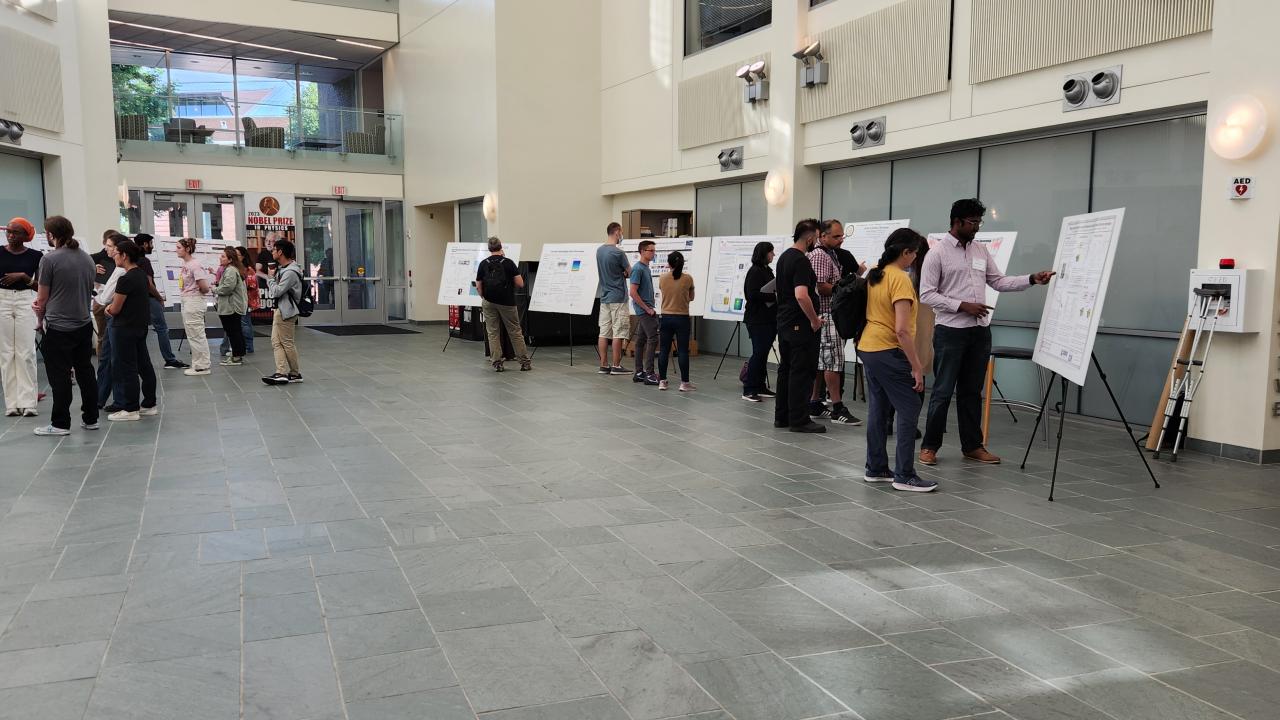 Attendees look at posters and speak with presenters in the Physics Research Building lobby