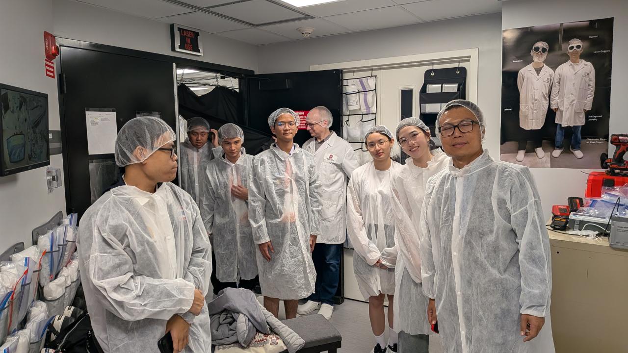 A group of Thai students in cleanroom clothing about to tour the NeXUS lab.