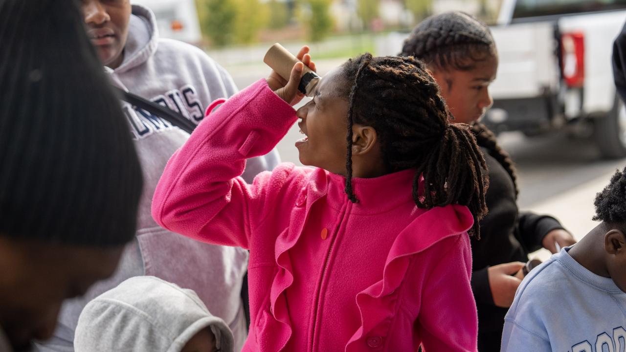 A child looking through a homemade spectroscope at NeXUS's 2025 West Fest booth