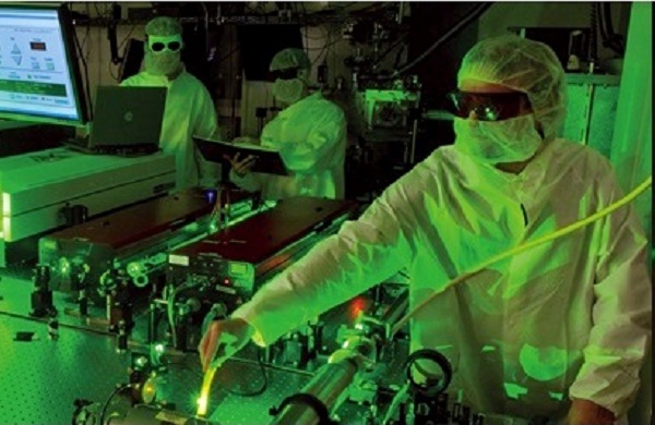 Scientist wearing personal protective equipment working in a darkened laser lab